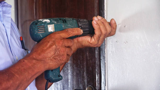 Home repairman is using a drill to drill a wall.